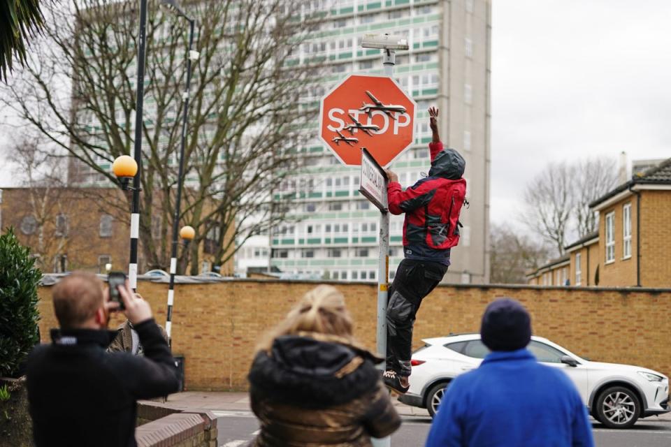 A person removes artwork by Banksy which was unveiled in Peckham, south-east London (PA Wire)