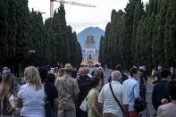 People gather to watch musicians performing in front of the Bergamo cemetery, Italy, Sunday, June 28, 2020. Italy bid farewell to its coronavirus dead on Sunday with a haunting Requiem concert performed at the entrance to the cemetery of Bergamo, the hardest-hit province in the onetime epicenter of the outbreak in Europe. President Sergio Mattarella was the guest of honor, and said his presence made clear that all of Italy was bowing down to honor Bergamo’s dead, “the thousands of men and women killed by a sickness that is still greatly unknown and continues to threaten the world.” (Claudio Furlan/LaPresse via AP)