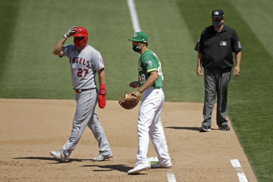 Oakland Athletics' Matt Olson (28) wears a mask as Los Angeles Angels' Mike Trout, left, also wears one while taking a lead off first base during the eighth inning of a baseball game Monday, July 27, 2020, in Oakland, Calif. (AP Photo/Ben Margot)