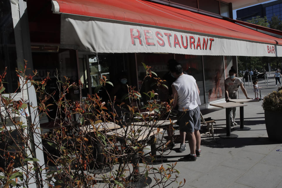 People prepare the terrace of their restaurant in Boulogne-Billancourt, outside Paris, Thursday, May 28, 2020. France is reopening its restaurants, bars and cafes starting next week as the country eases most restrictions amid the coronavirus crisis. Edouard Philippe defended the gradual lifting of lockdown up to now, saying the strategy was meant to avoid provoking a second wave. (AP Photo/Christophe Ena)