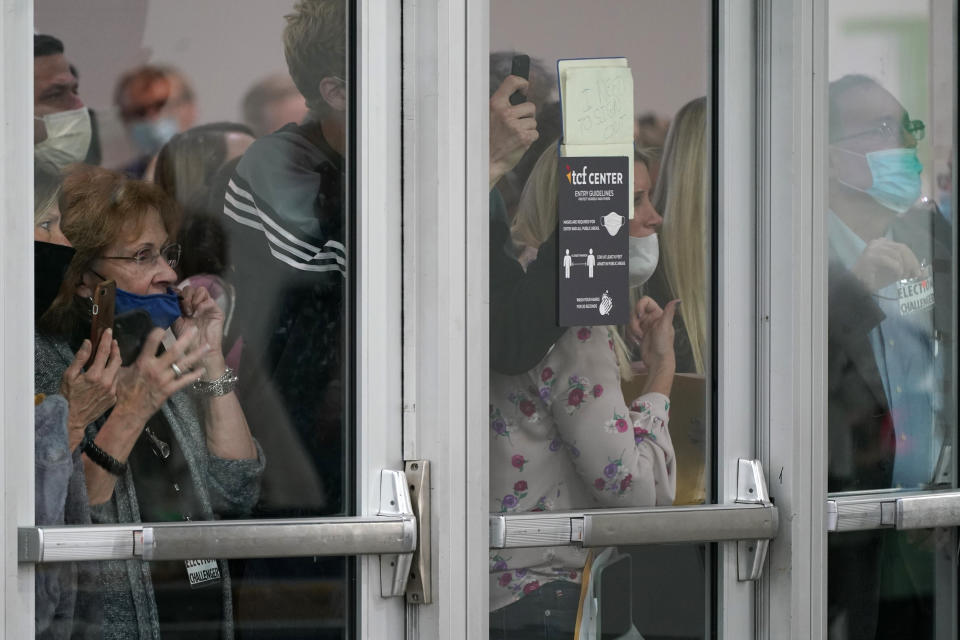 Election challengers look through the doors of the central counting board, Wednesday, Nov. 4, 2020, in Detroit. Officials were attempting to keep additional challengers from entering due to overcrowding. (AP Photo/Carlos Osorio)