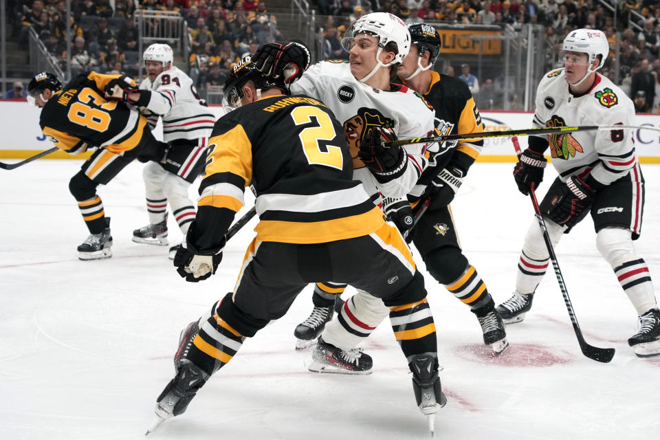 Chicago Blackhawks' Connor Bedard, center, works for position against Pittsburgh Penguins' Chad Ruhwedel (2) during the first period of an NHL hockey game in Pittsburgh, Tuesday, Oct. 10, 2023. (AP Photo/Gene J. Puskar)