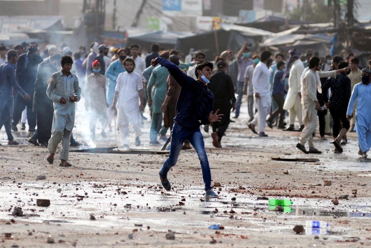 <p>An anti-French protester hurls stones towards police during a protest in Lahore, Pakistan</p> (REUTERS)