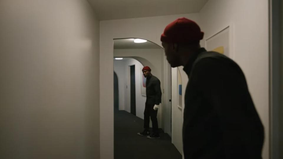 Anthony (Yahya Abdul-Mateen II) walks into a blank hallway and sees himself in a mirror in Candyman.