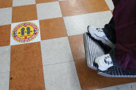 A social distancing sticker is on the floor while Edgar Gomez has his hair cut by George Garcia, owner of George's Barber Shop, Tuesday, July 14, 2020, in San Pedro, Calif. Gov. Gavin Newsom ordered that indoor businesses like salons, barber shops, restaurants, movie theaters, museums and others close due to the spread of COVID-19. (AP Photo/Ashley Landis)