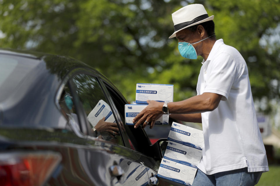 St. Louis area activist and pastor Rev. Darryl Gray hands boxes of face masks through an open car window to a church representative picking up protective equipment for their congregation, Thursday, May 28, 2020, in Hanley Hills, Mo. Gray is one of the organizers behind the effort to distribute about 150,000 masks to churches that plan to open as early as next week as restrictions surrounding the coronavirus outbreak ease. (AP Photo/Jeff Roberson)