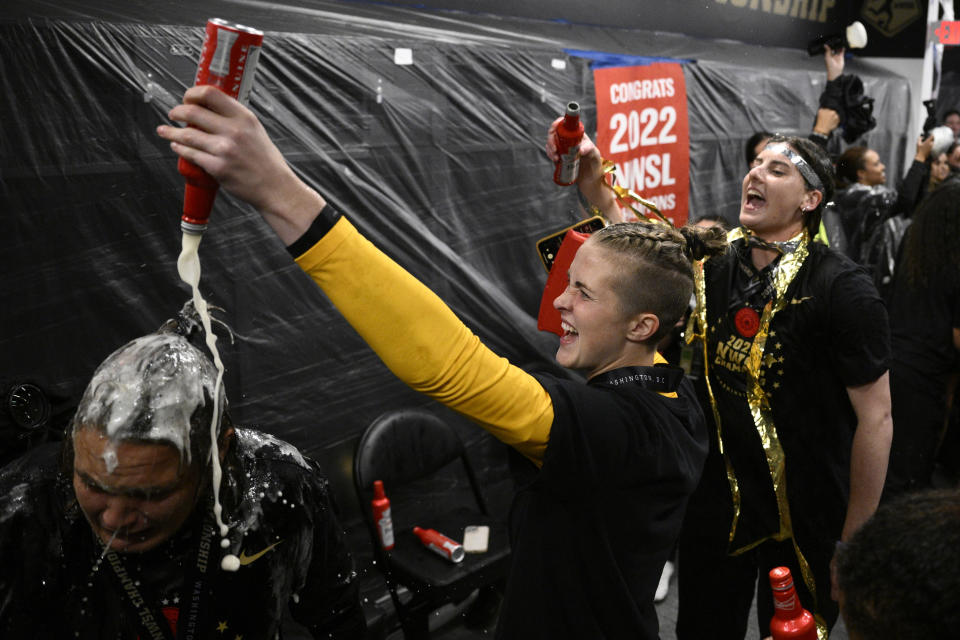 Portland Thorns FC goalkeeper Bella Bixby, in yellow, and others celebrate in the locker room after the NWSL championship soccer match against the Kansas City Current, Saturday, Oct. 29, 2022, in Washington. Portland won 2-0. (AP Photo/Nick Wass)