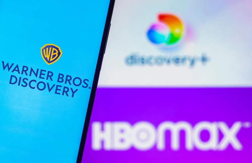 BRAZIL - 2022/08/05: In this photo illustration, the Warner Bros. Discovery logo is displayed on a smartphone screen and in the background, the HBO Max and Discovery Plus logos. (Photo Illustration by Rafael Henrique/SOPA Images/LightRocket via Getty Images)