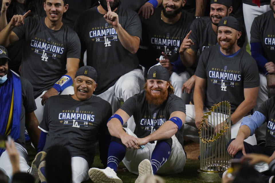 FILE - In this Tuesday, Oct. 27, 2020, file photo, Los Angeles Dodgers manager Dave Roberts, left foreground, sits beside third baseman Justin Turner as they pose for a group picture after the Dodgers defeated the Tampa Bay Rays 3-1 in Game 6 to win the baseball World Series in Arlington, Texas. Baseball nearly made it through its version of playoff bubbles unscathed; two innings before the World Series ended, Justin Turner of the now-champion Los Angeles Dodgers Turner was pulled from the game after MLB was notified that he had tested positive for COVID-19. (AP Photo/Eric Gay, File)