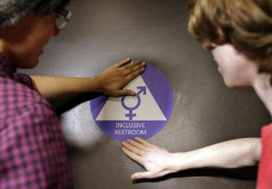 Destin Cramer and Noah Rice place a sticker on the door at the opening of a gender-neutral bathroom at Nathan Hale High School in Seattle, on May 17, 2016. (Photo: Elaine Thompson/AP)