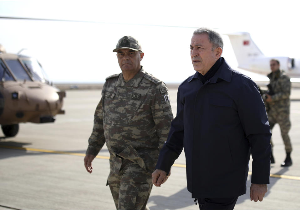 Turkey's National Defence Minister Hulusi Akar, right, arrives to inspect troops at the border with Syria, in Hatay, Turkey, Monday, Feb. 3, 2020. Turkey hit targets in northern Syria, responding to shelling by Syrian government forces that killed at least eight Turkish military personnel, Turkish President Recep Tayyip Erdogan said Monday. A Syrian war monitor said 13 Syrian troops were also killed.(Turkish Defence Ministry via AP, Pool)