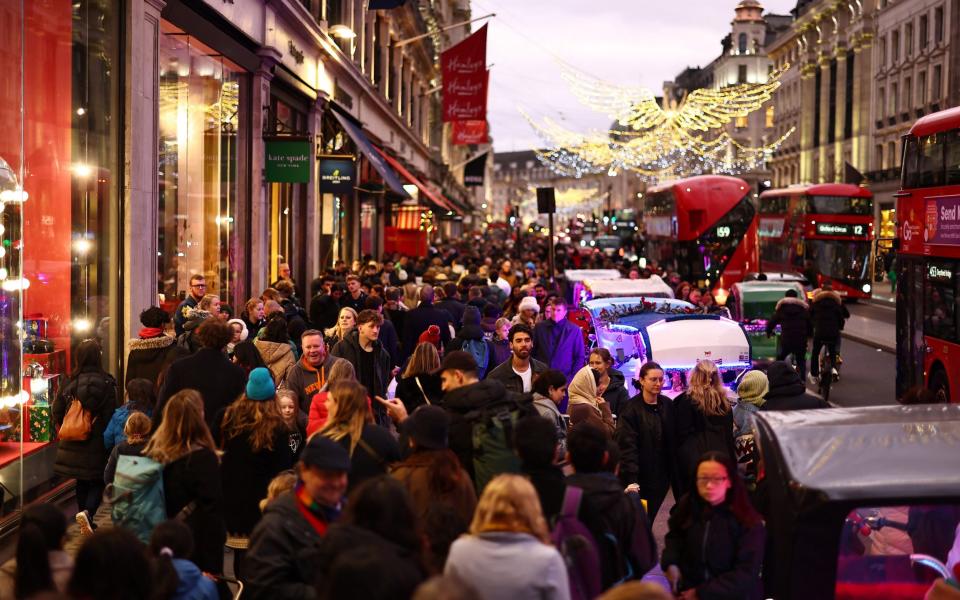 Shoppers walk past shops on Regent Street in London on the final weekday before Christmas