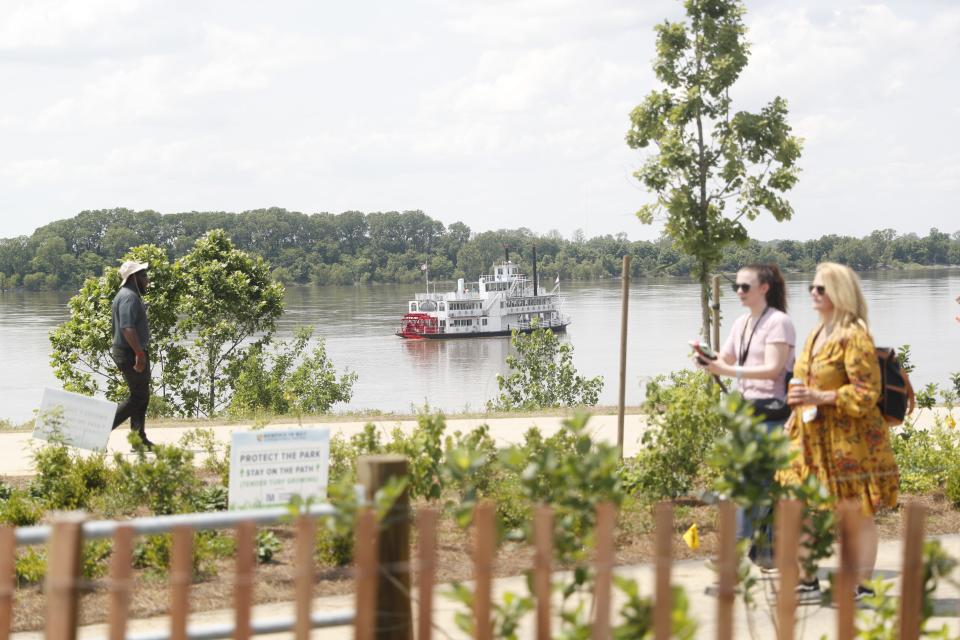 A riverboat treads the Mississippi River as attendees walk toward BBQ Alley on May 18, 2023, during the Memphis in May World Championship Barbecue  Cooking Contest at Tom Lee Park in Downtown Memphis.