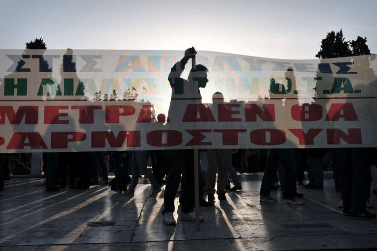 A protester's silhouette is seen behind a banner reading: "The measures won't apply", as demonstrators gather in front of the parliament in Athens on April 28, 2013