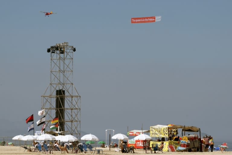 An aircraft carrying a banner saying 'The Queen is in the Palace' is seen flying over the stage at Copacabana Beach (Pablo PORCIUNCULA)