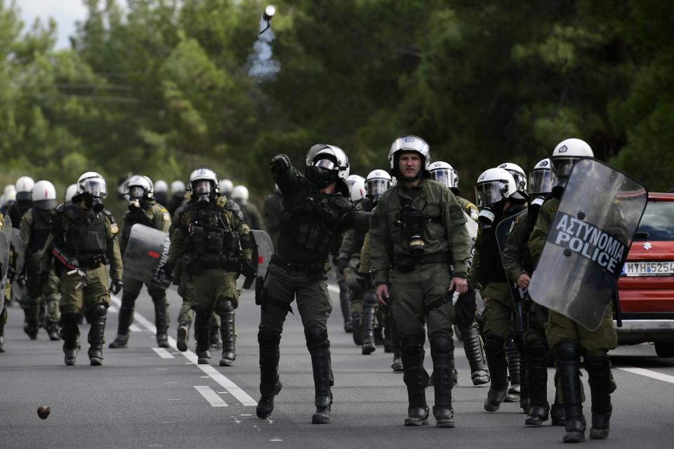 A riot policeman throws a tear gas canister at local protesting residents during clashes in Karava near the area where the government plans to build a new migrant detention center, on the northeastern Aegean island of Lesbos, Greece, Wednesday, Feb. 26, 2020. Local authorities declared a 24-hour strike on two eastern Greek islands Wednesday to protest government plans to build new migrant detention camps there. (AP Photo/Michael Varaklas)