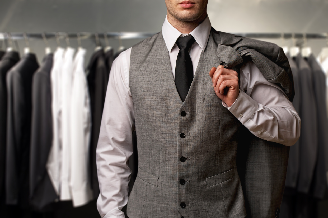 Closeup of man wearing a suit in front of a rack of suits
