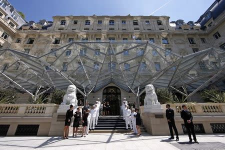 Employees pose on the steps outside the Peninsula Paris luxury hotel during a press presentation in Paris in this June 24, 2014 file picture. REUTERS/Benoit Tessier/Files