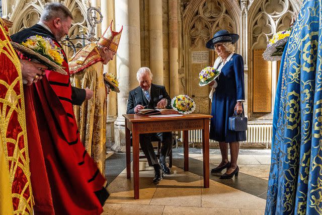 CHARLOTTE GRAHAM/POOL/AFP via Getty Images King Charles and Queen Camilla sign the book as they attend the Royal Maudy Service in April 2023