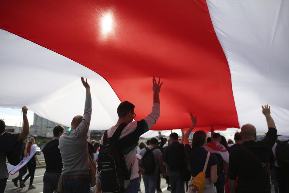 Protesters carry a giant old Belarusian national flag during a Belarusian opposition supporters' rally protesting the official presidential election results in Minsk, Belarus, Sunday, Sept. 13, 2020. Protests calling for the Belarusian president's resignation have broken out daily since the Aug. 9 presidential election that officials say handed him a sixth term in office. (TUT.by via AP)