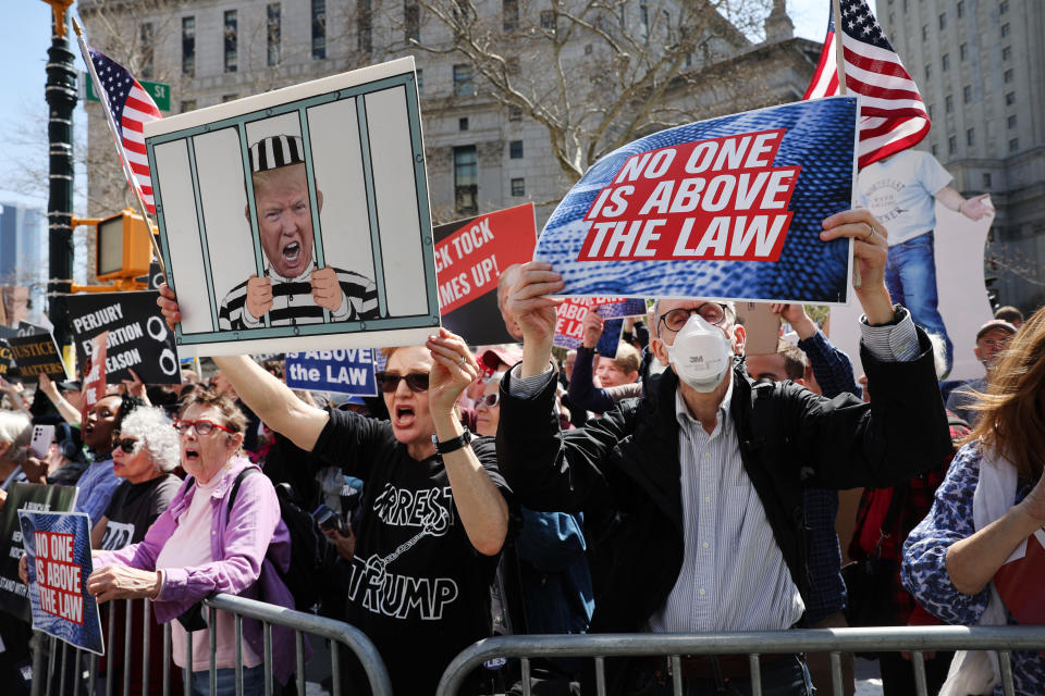 Opponents of Trump outside the Manhattan Criminal Courthouse hold up signs reading: No one is above the law.