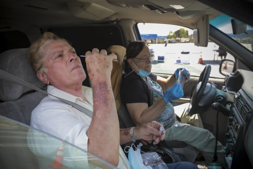 SANTA ANA , CA - AUGUST 22: Daniel Mendoza, left, and Linda Mendoza take a coronavirus test at a drive-in free COVID-19 testing site established by City of Santa Ana and Rancho Santiago Community College district in Santa Ana College parking lot on Saturday, Aug. 22, 2020 in Santa Ana , CA. (Irfan Khan / Los Angeles Times)