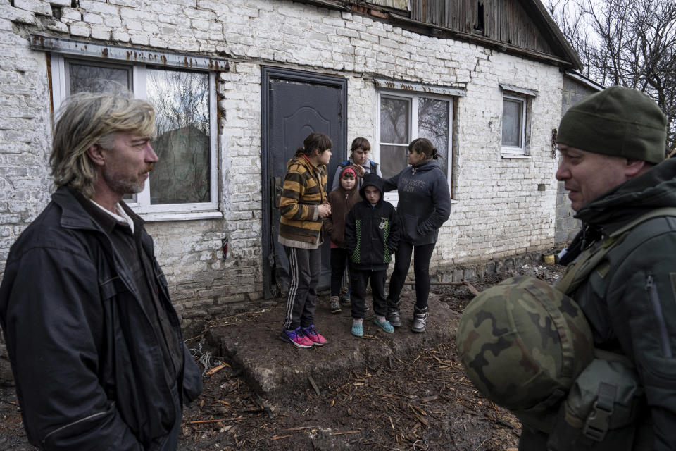 A Ukrainian police officer of the White Angels unit, tries to persuade a family to evacuate to a safe area in Krasnohorivka, Ukraine, Tuesday, Feb. 21, 2023. For months, authorities have been urging civilians in areas near the fighting in eastern Ukraine to evacuate to safer parts of the country. But while many have heeded the call, others -– including families with children -– have steadfastly refused.(AP Photo/Evgeniy Maloletka)