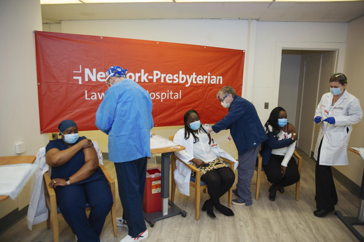 FILE - In this Friday, Jan. 8, 2021, file photo doctors inject sisters Claudia Scott-Mighty, left, Althea Scott-Bonaparte, who are patient care directors, and Christine Scott, an ICU nurse, with their second shot of the Pfizer vaccine at NewYork-Presbyterian Lawrence Hospital, in Bronxville, N.Y. The private New York-Presbyterian hospital system announced in June that it will require its 48,000 employees to be vaccinated unless they have a valid exemption. Workers in New York City-run hospitals and health clinics will have to get vaccinated or get tested weekly under a policy announced Wednesday, July 21, to battle a rise in COVID-19 cases fueled by the highly contagious delta variant. (AP Photo/Kevin Hagen, File)