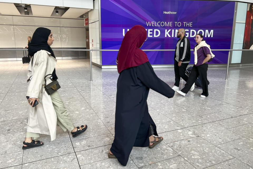 People walk past a sign saying 'welcome to the United Kingdom' at the arrivals of Heathrow Airport, in London, Monday, Aug. 28, 2023. Britain’s air traffic control system says it is experiencing a “technical issue” that could delay flights on Monday, the end of a holiday weekend and a busy day for air travel. (AP Photo/Alberto Pezzali)