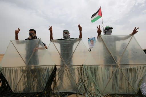 Palestinians pose behind makeshift fire kites in Khan Yunis in the southern Gaza Strip on May 4, 2018 before launching them over the border into Israel