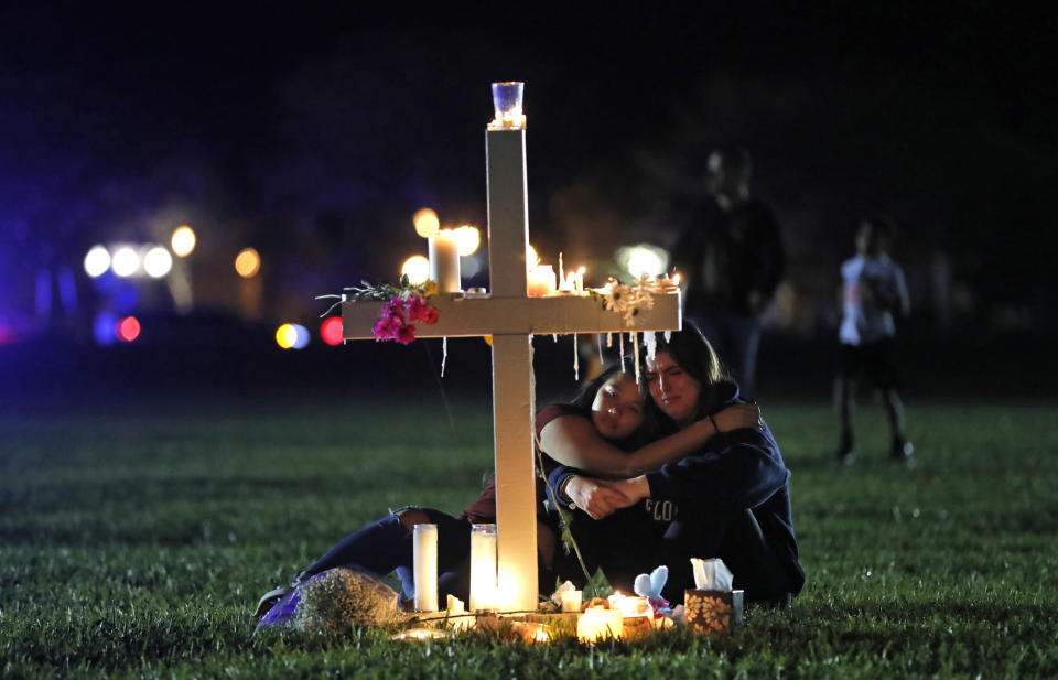 FILE - In this Feb. 15, 2018 file photo, people comfort each other as they sit and mourn at one of seventeen crosses, after a candlelight vigil for the victims of the shooting at Marjory Stoneman Douglas High School, in Parkland, Fla. Sorrow is reverberating across the country Sunday, Feb. 14, 2021, as Americans joined a Florida community in remembering the 17 lives lost three years ago in the Parkland school shooting massacre. President Joe Biden used the the occasion to call on Congress to strengthen gun laws, including requiring background checks on all gun sales and banning assault weapons. (AP Photo/Gerald Herbert, File)