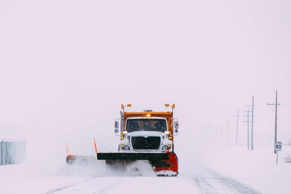 a snowplow clearing snow on a highway during a blizzard