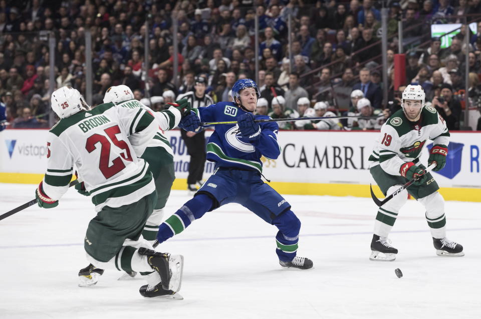 Vancouver Canucks' Elias Pettersson, center, of Sweden, is checked by Minnesota Wild's Matt Dumba (24) during the second period of an NHL hockey game Wednesday, Feb. 19, 2020, in Vancouver, British Columbia. (Darryl Dyck/The Canadian Press via AP)