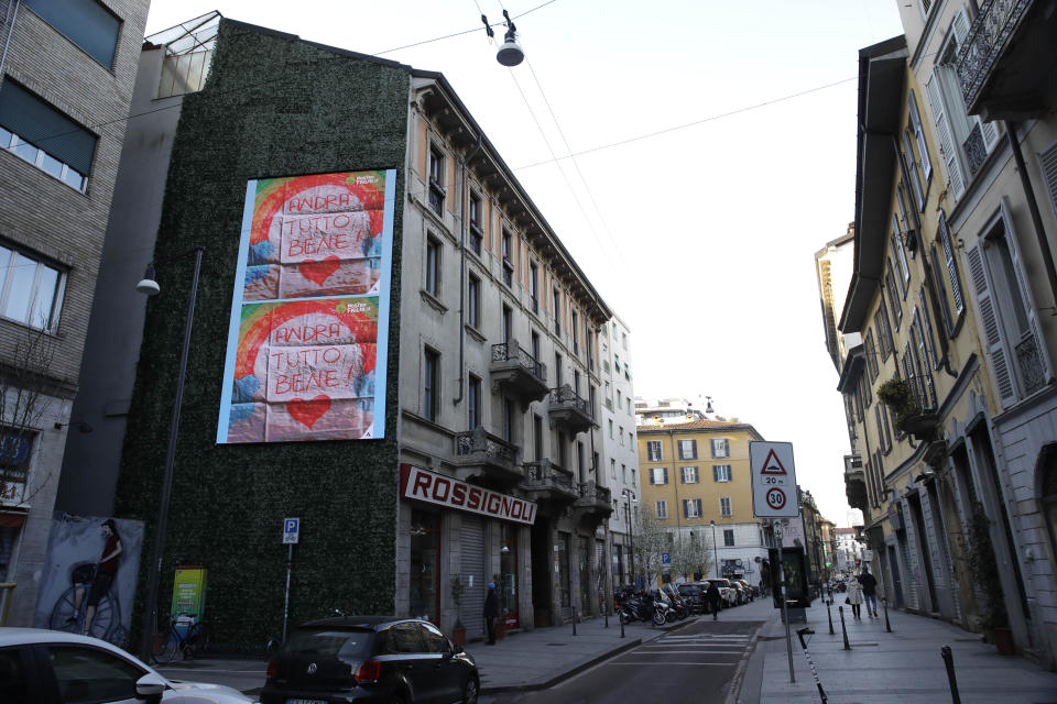 In this photo taken on Friday, March 13, 2020, giant drawings of rainbows reading in Italian, "Everything will be alright", hang on the side of a building in Milan, Italy. The nationwide lockdown to slow coronavirus is still early days for much of Italy, but Italians are already are showing signs of solidarity. This week, children’s drawings of rainbows are appearing all over social media as well as on balconies and windows in major cities ready, ‘’Andra’ tutto bene,’’ Italian for ‘’Everything will be alright.’’ For most people, the new coronavirus causes only mild or moderate symptoms. For some, it can cause more severe illness, especially in older adults and people with existing health problems. (AP Photo/Luca Bruno)