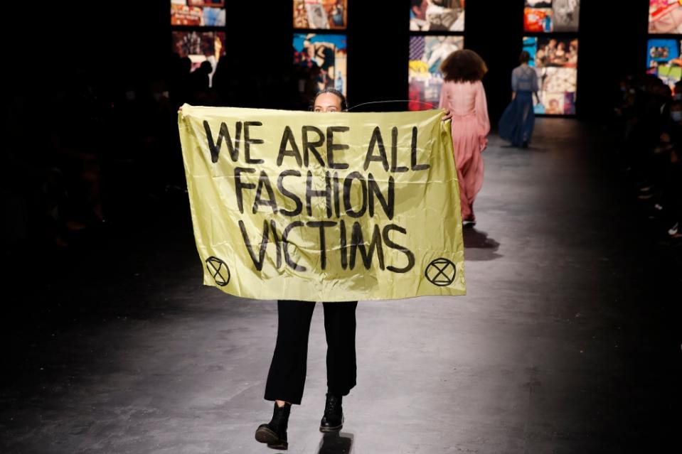 A climate change activist protests on the Dior runway. - Credit: WWD