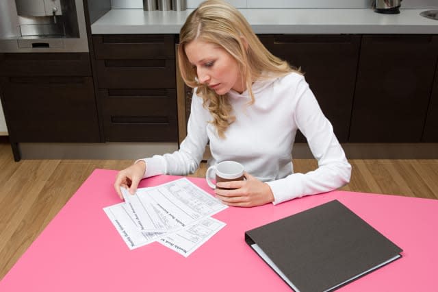 AR58EK Woman reading bank statements Woman; reading; bank; statements; paperwork; paper; material; document; reading; bank; stat