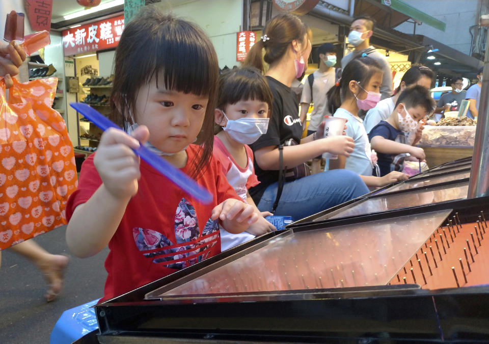 Children wear face masks to help curb the spread of the coronavirus as they play carnival games at a night market in Taipei, Taiwan, Sunday, May 3, 2020. (AP Photo/Chiang Ying-ying)