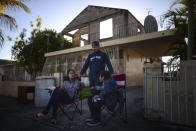 Reynaldo Gonzalez, center, nephew of 73 year-old Nelson Martinez, who died after a wall collapsed during an earthquake, waits with family members for Martinez's body to be removed in Ponce, Puerto Rico, Tuesday, Jan. 7, 2020. (AP Photo/Carlos Giusti)