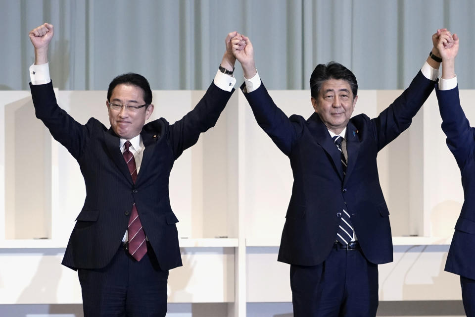 FILE - Former Japan's Foreign Minister Fumio Kishida, left, and Prime Minister Shinzo Abe celebrate after Chief Cabinet Secretary Yoshihide Suga was elected as new head of Japan's ruling party at the Liberal Democratic Party's (LDP) leadership election in Tokyo on Sept. 14, 2020. Assassinated former Prime Minister Shinzo Abe was perhaps the most divisive leader in recent Japanese history. He was also the longest serving and, by many estimations, the most influential. (AP Photo/Eugene Hoshiko, Pool, File)