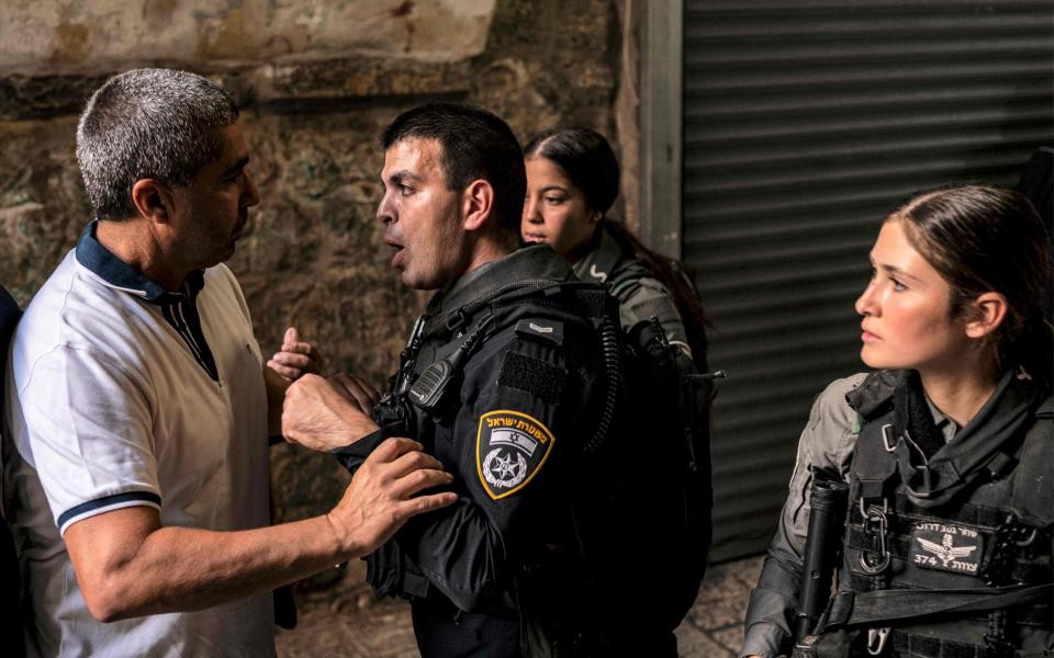 An Israeli policeman argues with a man as Muslim worshippers are denied entry to the Aqsa mosque compound