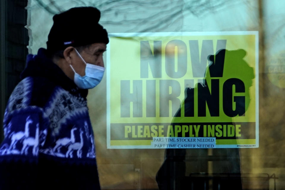 A shopper wears a face mask and he walks past a store displaying a hiring sign in Wheeling, Ill., Saturday, Nov. 28, 2020. More than 65,000 unemployment claims were filed statewide last week due to COVID-19 in Illinois. (AP Photo/Nam Y. Huh)