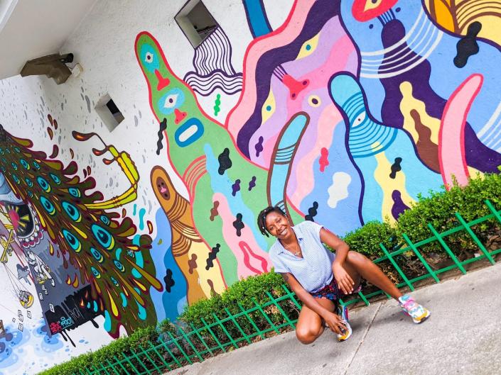 amber perched in front of colorful street murals in mexico