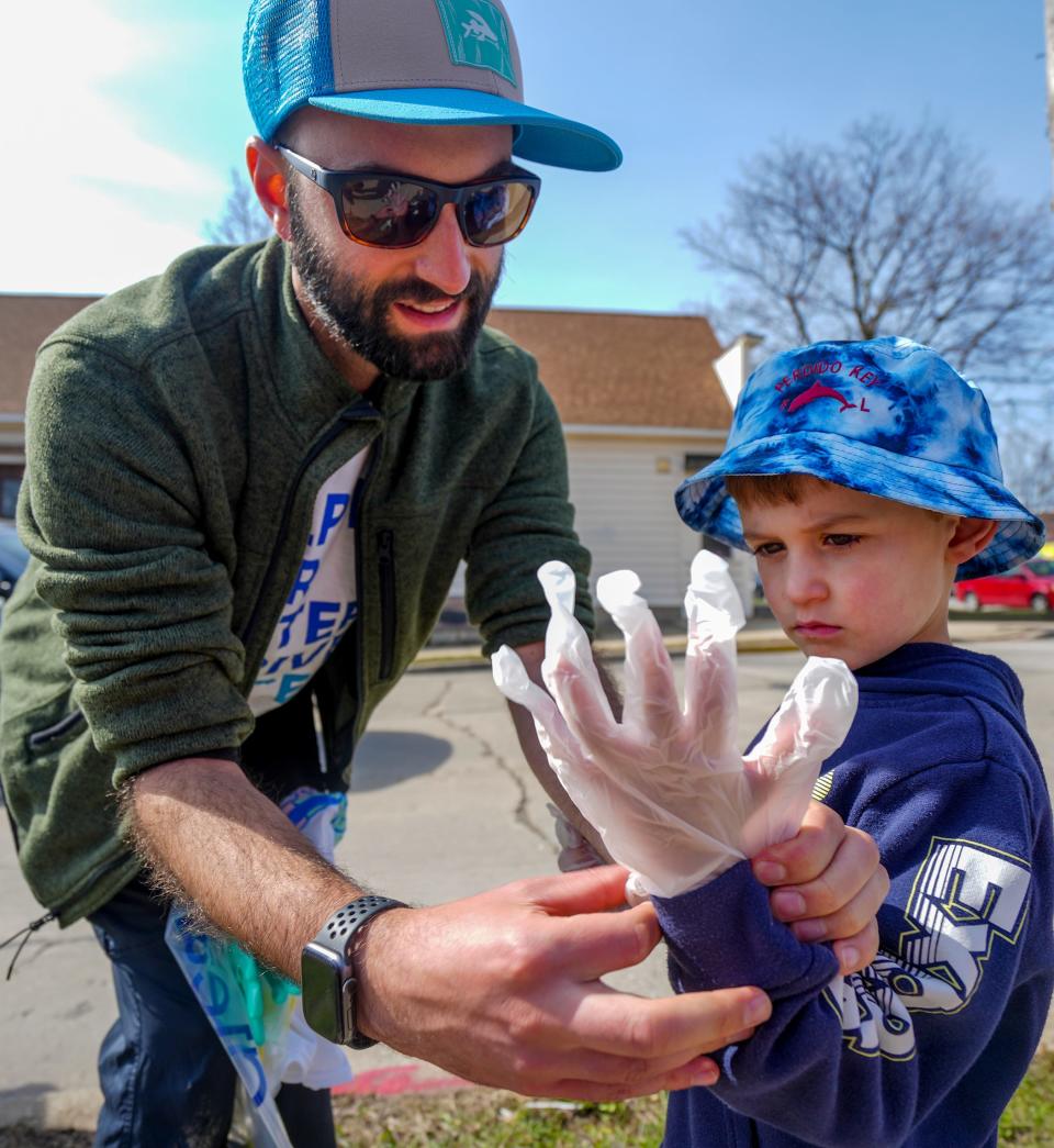 Mike Montenegro helps his 5-year-old son, Rico, put on a glove to help clean up the community during the 27th annual Milwaukee Riverkeeper Spring Cleanup Saturday along South 10th Street in Milwaukee.