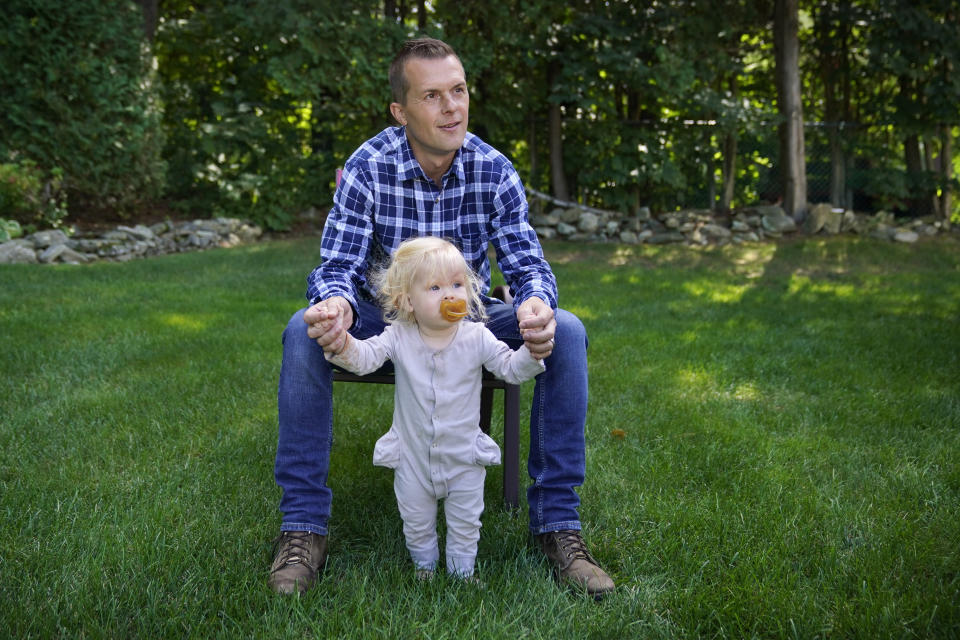 U.S. Rep. Jared Golden, D-Maine, with his daughter Rosemary, speaks to a reporter at his home, Thursday, Sept. 1, 2022, in Lewiston, Maine. Golden is being challenged by Republican Bruce Poliquin in the November election. (AP Photo/Robert F. Bukaty)