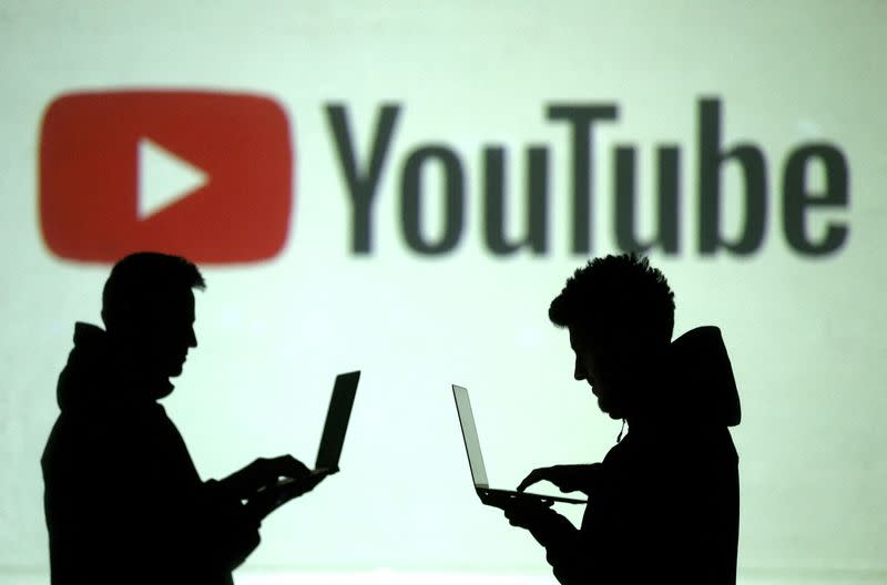 FILE PHOTO: Silhouettes of mobile device users are seen next to a screen projection of Youtube logo in this picture illustration