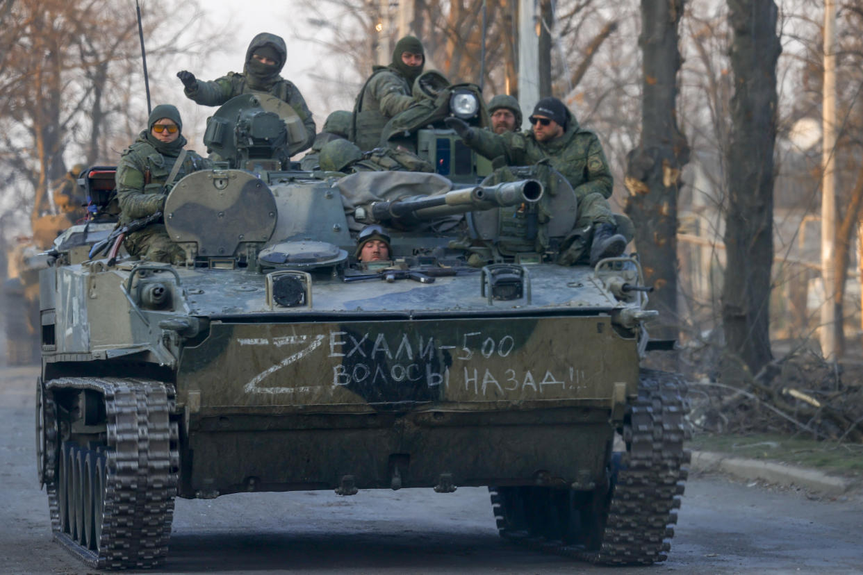 A half-dozen Russian soldiers huddle against the cold on an advancing tank.