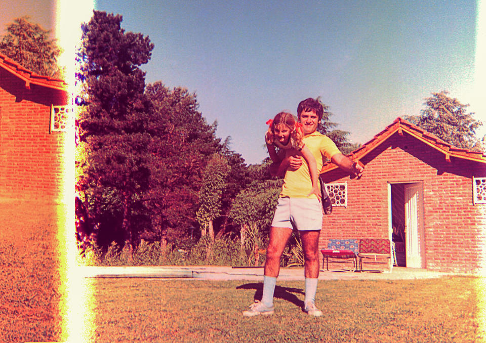 a daughter climbing over her dad as they play outside