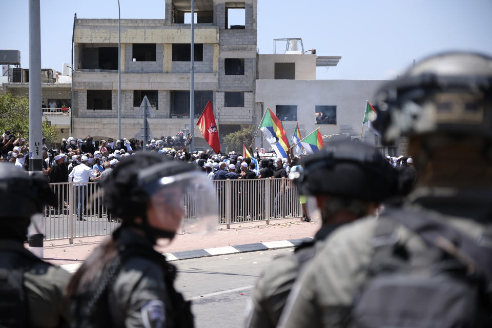 Israeli police in riot gear stand near Druze protesters as thousands took part in the demonstrations against the construction of massive wind turbines in the Golan Heights,, Wednesday, June 21, 2023. Israeli police fired tear gas, sponge-tipped bullets and a water canon during the mass demonstrations by Druze Arabs — a rare burst of violence in the normally quiet area. (AP Photo/Fadi Amun) **ISRAEL OUT**
