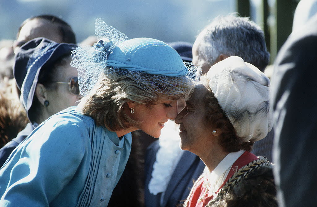 Princess Diana rubbing noses — the traditional Maori greeting — with a Maori woman in New Zealand, wearing her turquoise silk suit. (Photo: Getty)