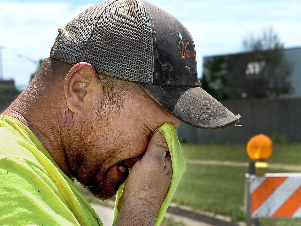 Was Con Construction worker Isaac Diesselhorst uses his shirt to wipe the sweat from his face while working on a sidewalk ramp at the corner of 14th and Mason streets on Wednesday.